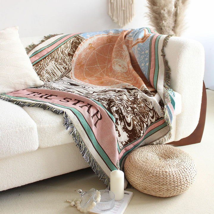 VibeCore The Star Tarot Woven Blanket draped over a couch, showcasing its celestial-inspired design with vibrant, reversible patterns on soft, luxurious 100% combed cotton.