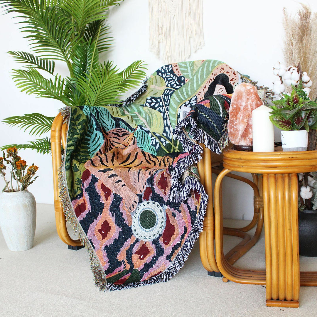 Tiger Lounge Woven Blanket on a chair, showcasing its vibrant, artistic-inspired design. Crafted from 100% combed cotton, this soft and versatile blanket adds a bold touch to your space.