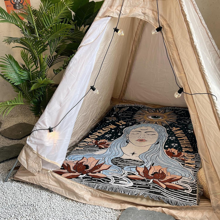 VibeCore Tomorrow Is Another Day Woven Blanket spread out on the floor inside a tent, showcasing its vibrant, spiritual design and reversible patterns.