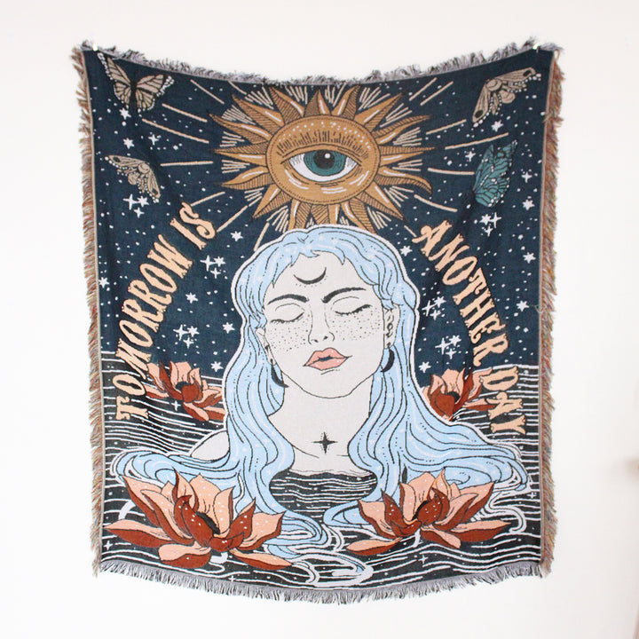 VibeCore Tomorrow Is Another Day Woven Blanket displayed flat, showcasing its spiritual-inspired design. The soft cotton material features vibrant, cosmic patterns, making it a standout piece for any room.