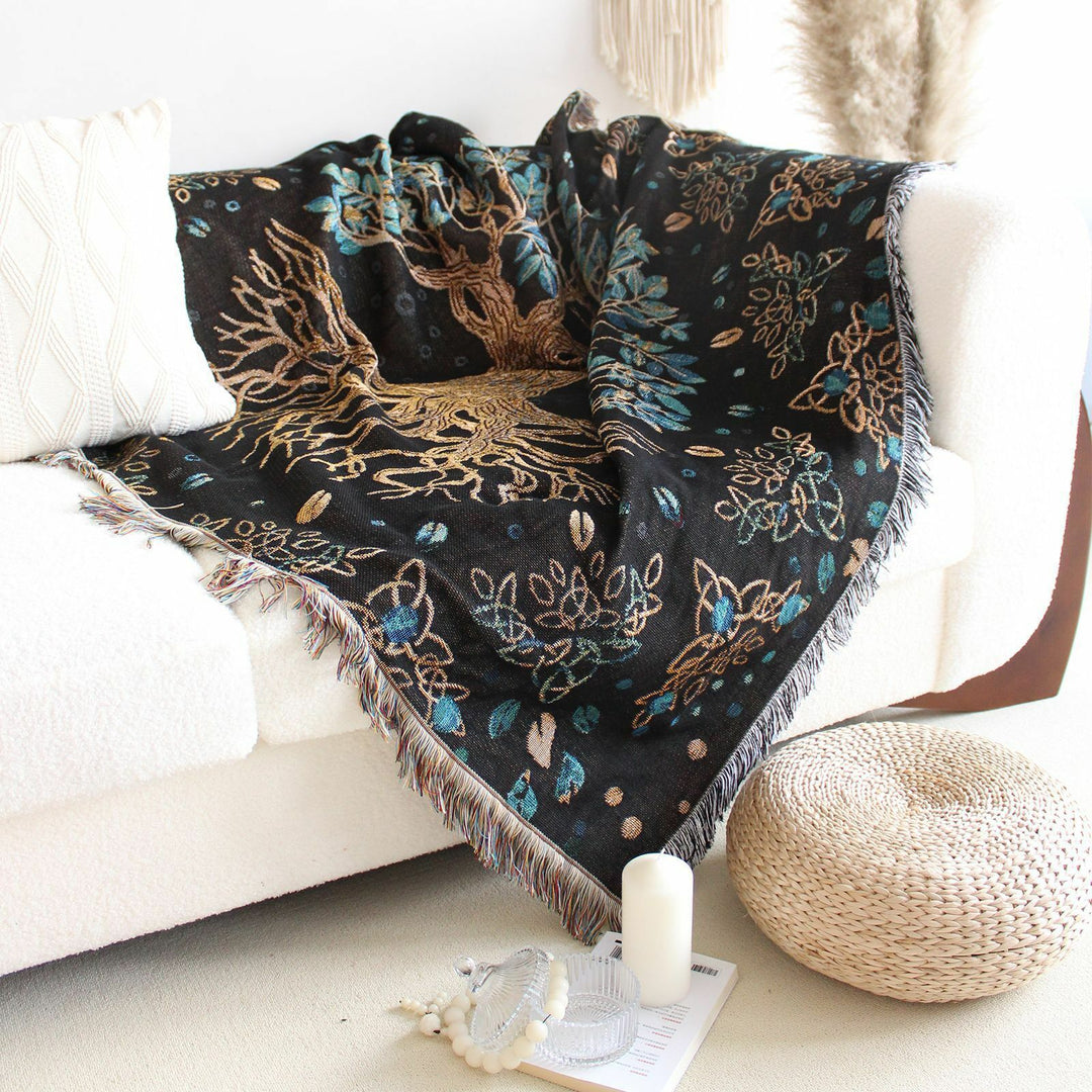 VibeCore Tree of Life Woven Blanket draped over a couch, showcasing its symbolic tree design and soft cotton texture. The blanket adds a cozy, serene touch to the space with its reversible pattern, offering versatility and style.