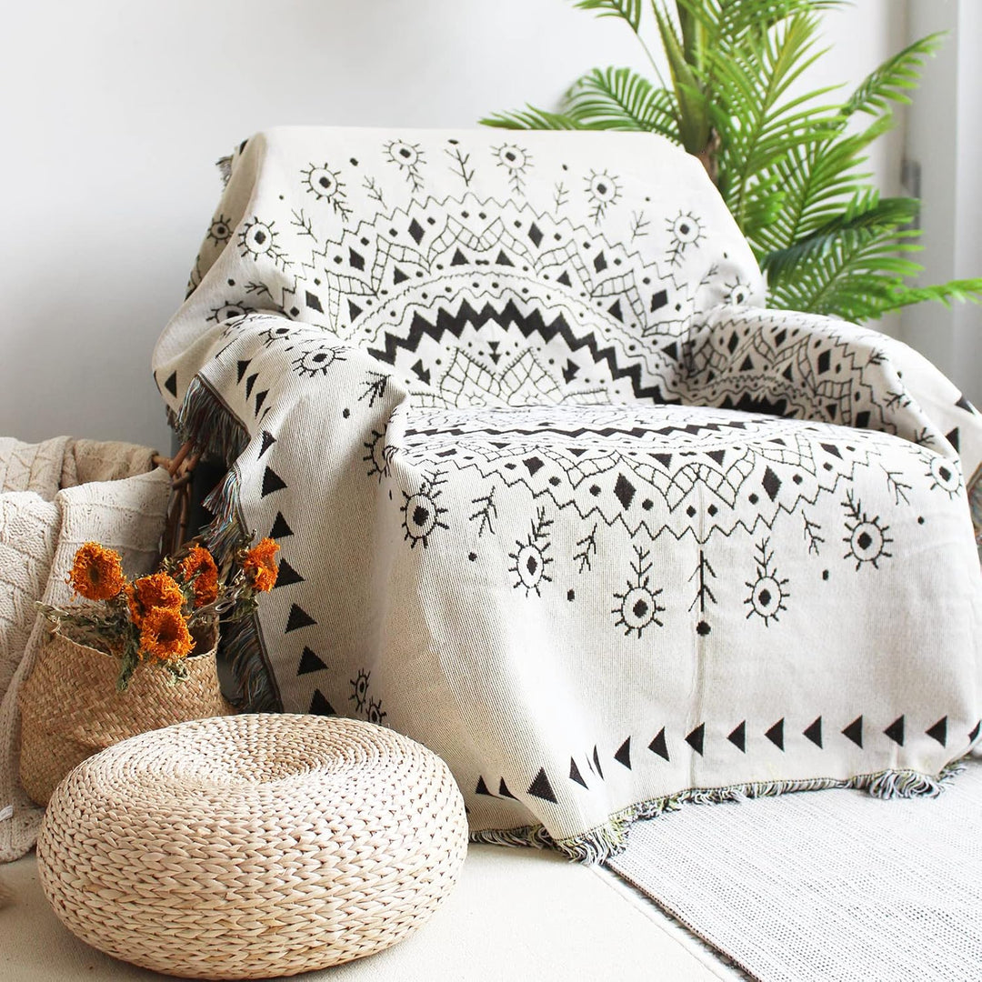 VibeCore White Boho Mandala Woven Blanket draped over chair, featuring a calming boho mandala design. Made from soft, breathable 100% combed cotton, it adds a vibrant, artistic touch and cozy bohemian flair to your space.