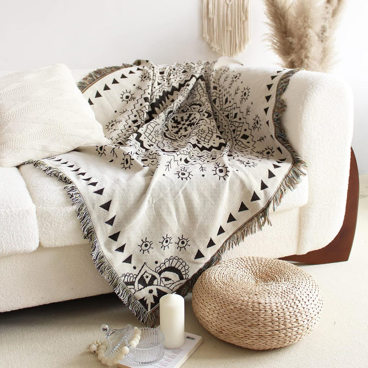 VibeCore White Boho Mandala Woven Blanket draped over couch, featuring a calming boho mandala design. Made from soft, breathable 100% combed cotton, it adds warmth, vibrant style, and a touch of bohemian charm to your living space.