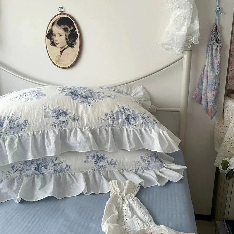 Decorative bed with ruffled pillows and floral headboard in a bedroom setting.