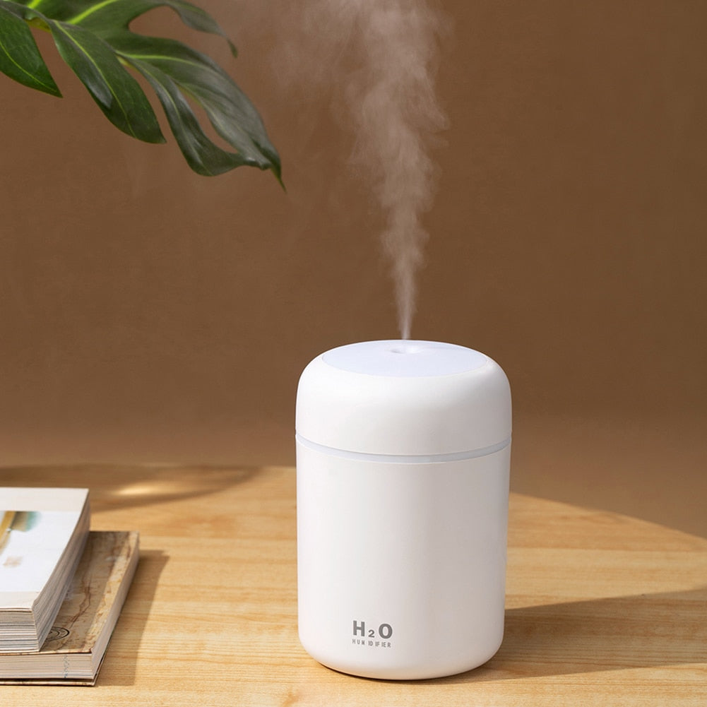 The white aromatherapy diffuser placed elegantly on a table, releasing a calming mist and emitting soft LED light, enhancing the room's ambiance.