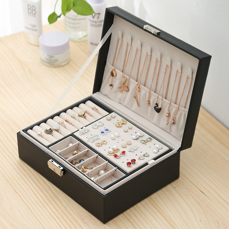 VibeCore Multi-Layer Jewelry Box in Black, open angled aerial view, showcasing its sleek, lockable design with two layers and a bonus top storage component. Featuring compartments for rings, necklaces, earrings, and more, perfect for travel or everyday use.
