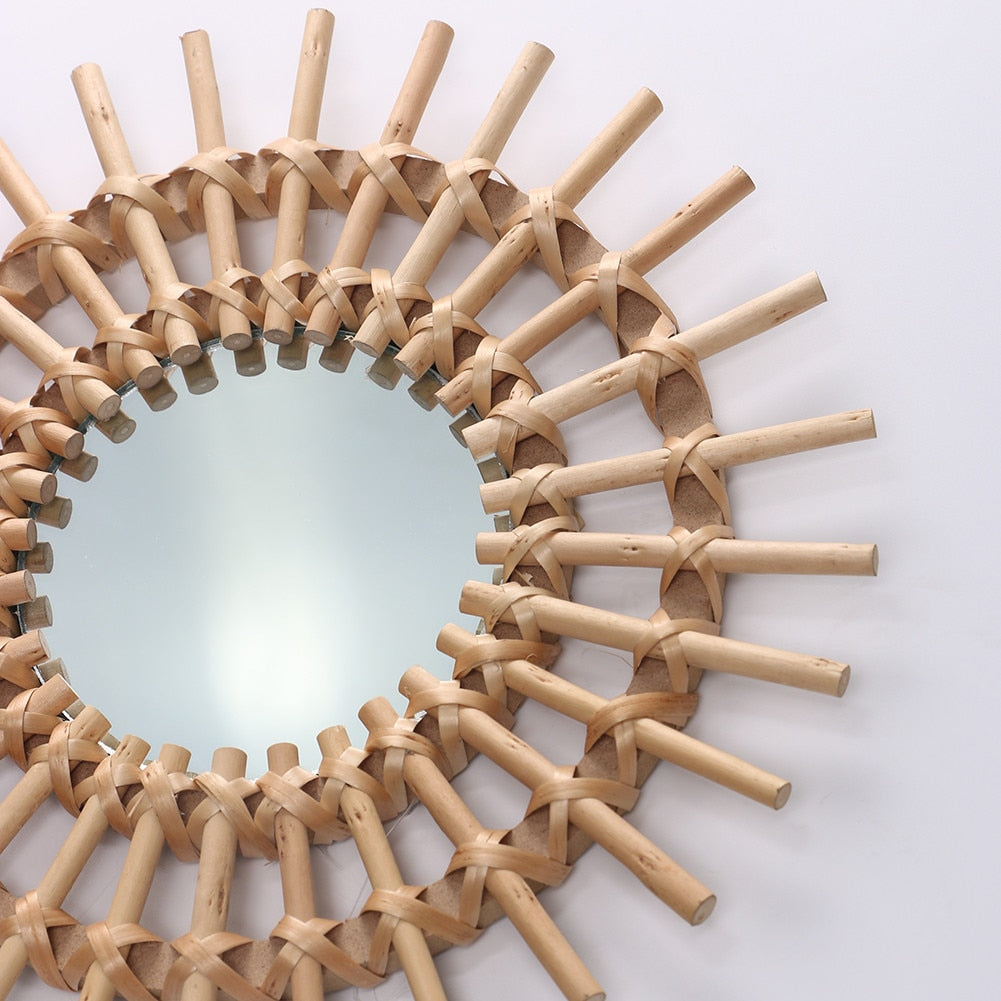 VibeCore Rattan Sun Mirror angled close-up, highlighting the intricate handwoven rattan frame and clear reflective glass with a detailed view of the sunburst design.