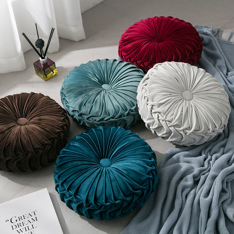 VibeCore Round Velvet Cushions in various colors, stacked on the floor, showcasing their plush texture and elegant design.